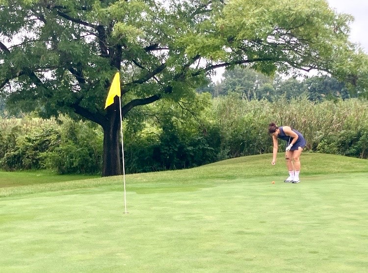 Golfer putting on green near flag