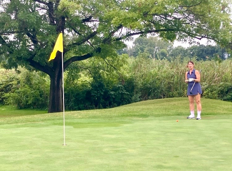Golfer putting on green with yellow flag