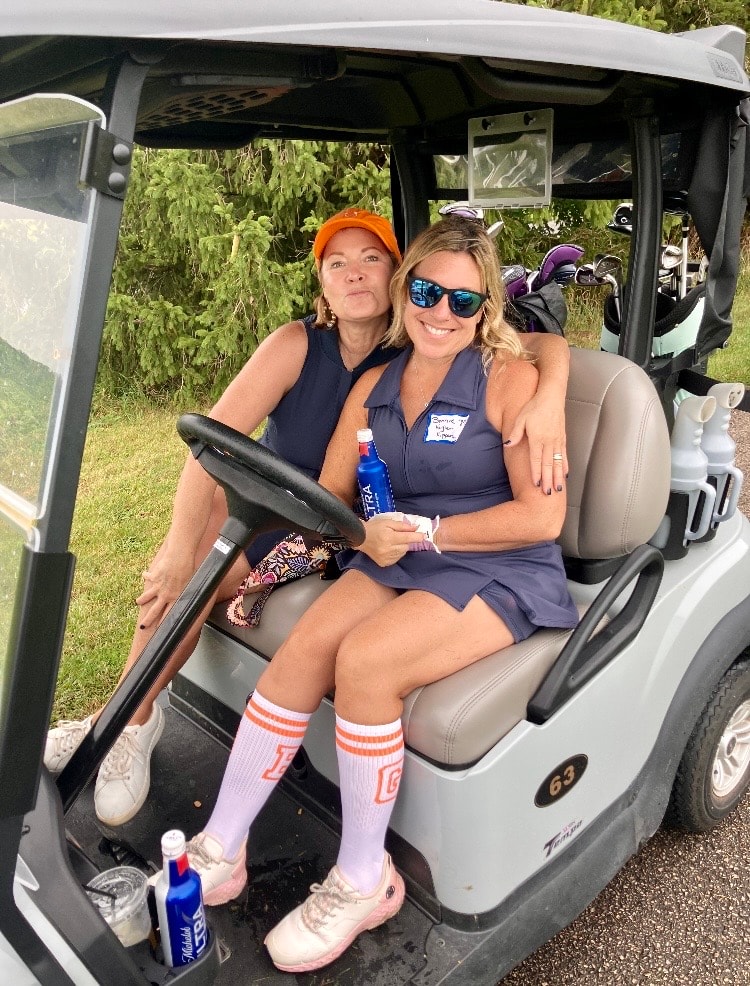 Two women in golf cart smiling