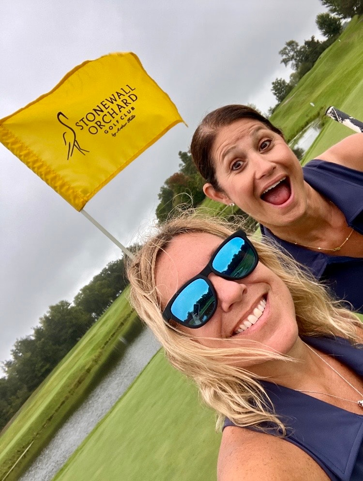 Women at golf course holding flag selfie