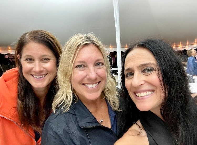 Three women smiling at outdoor event