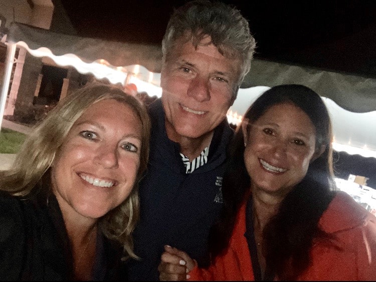 Three people smiling at night event