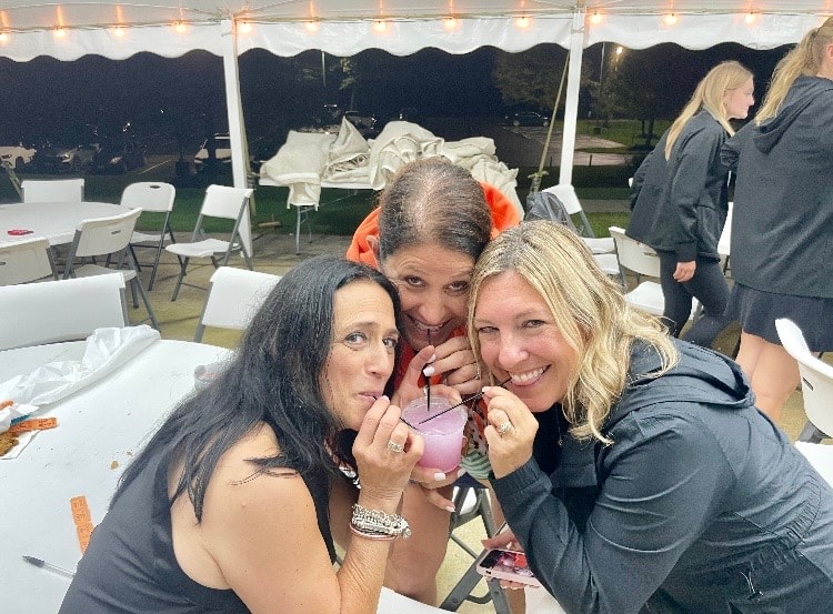 Three women posing together at outdoor tent event