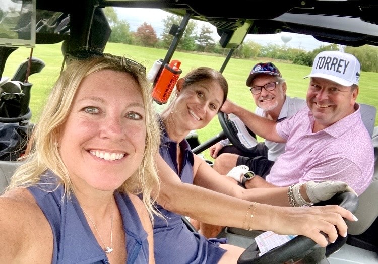 Four golfers smiling in golf cart
